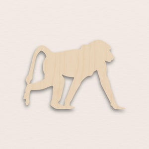 Puede incluir: Silueta de babuino de madera clara. El babuino se representa en posición de caminar, con la cola curvada hacia arriba. La veta de la madera es visible, añadiendo textura a la forma del babuino. El babuino es de color marrón claro.