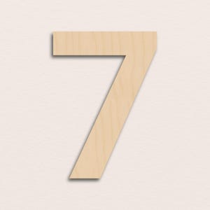 Puede incluir: Un recorte de madera con el número siete en color beige claro. El número se muestra sobre un fondo neutro. El número es una sola pieza de madera con una superficie plana y lisa.