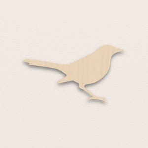 Puede incluir: Silueta de pájaro de madera clara. El recorte presenta una cola larga, un pico curvo y patas detalladas. El pájaro está sobre un fondo neutro, con un acabado liso.