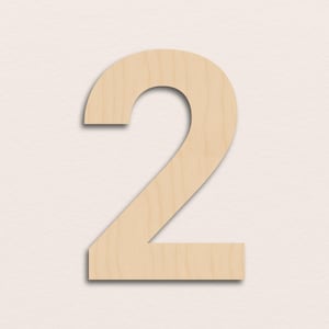 Puede incluir: Un recorte de madera del número dos en color beige claro. El número se muestra sobre un fondo neutro. El recorte tiene una superficie lisa y una ligera sombra, lo que le da una apariencia tridimensional. Ideal para manualidades y decoración del hogar.