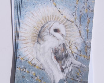 May include: A white barn owl with brown markings sits on a wooden post. The owl is surrounded by a halo of light and is perched in front of a blue and white background with yellow flowers.