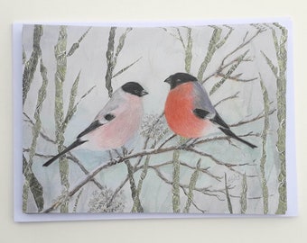 May include: A watercolor painting of two birds perched on a branch. The bird on the left is pink with a black head, and the bird on the right is red with a gray head. The background is a light blue with green branches.