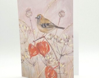 May include: A greeting card featuring a watercolor painting of a small bird perched on a branch with orange berries. The background is a soft, muted pink with delicate floral details. The card is blank inside.