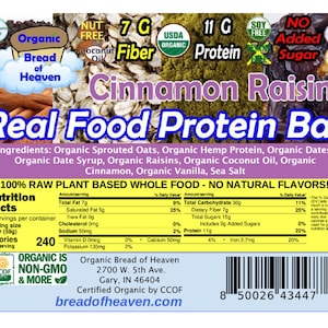 May include: A product label for a Cinnamon Raisin Real Food Protein Bar. The label features the brand name "Bread of Heaven" and highlights key nutritional information, including 7g of fiber and 11g of protein. The bar is certified organic and non-GMO.