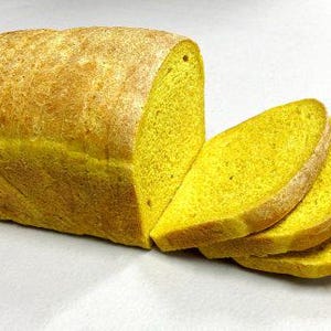 May include: A loaf of golden-yellow bread, partially sliced to reveal the vibrant interior. The bread has a slightly crusty exterior and a soft, airy texture. Several slices are visible, showcasing the bread's color and crumb.