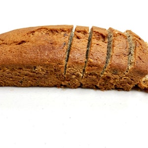 May include: A loaf of sliced brown bread on a white surface.