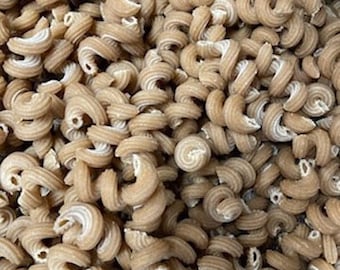 May include: A close-up image of a large bowl of brown and white pasta. The pasta is in the shape of a spiral.
