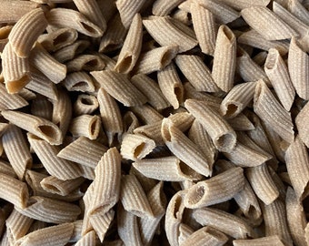 May include: A close-up view of a pile of brown whole wheat penne pasta.