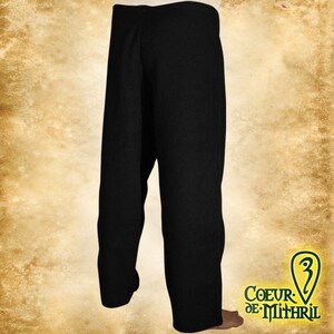 May include: Black pants with a straight leg and a wide waistband. The pants are made of a thick, woven fabric.