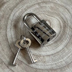 May include: A silver padlock with two keys. The padlock is engraved with the text "we fell in love 17.06.2019".