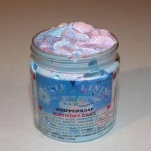 May include: A blue and pink whipped soap in a jar with a label that reads "Whipped Soap Birthday Cake" and "Lillie Lining Bath Body Boutique".