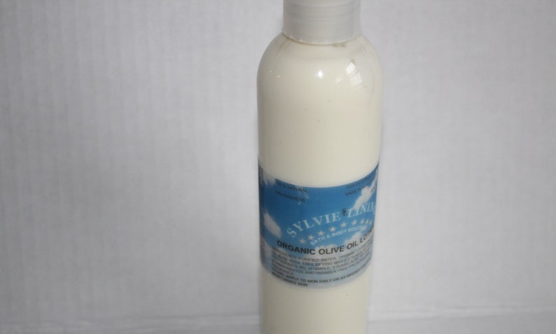Puede incluir: Una botella de pl&aacute;stico blanca de loci&oacute;n de aceite de oliva org&aacute;nico con una etiqueta azul que dice "Sylvie Clinic" y "Loci&oacute;n de aceite de oliva org&aacute;nico".