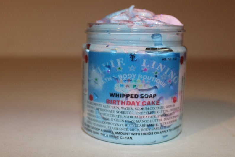 May include: A clear jar of whipped soap with a blue and pink swirl. The label reads "Whipped Soap Birthday Cake" and lists ingredients. The jar is labeled "Linie Bath Body Boutique".