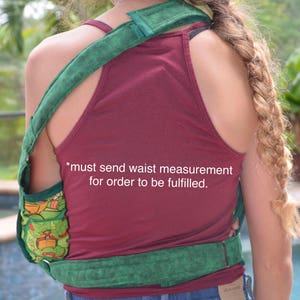 May include: A green and black fabric sling with a turtle design. The sling is worn over a red tank top. *must send waist measurement for order to be fulfilled.*