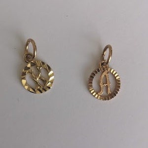 May include: Two gold-colored pendants with a circular design. The pendants feature the letters "R" and "A" in a cutout style.