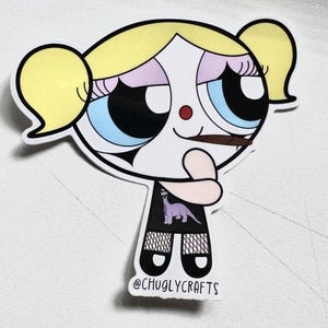 May include: A cartoon sticker of a girl with blonde pigtails, wearing a black dress with a purple dinosaur graphic, holding a brown cigarette. The sticker has a white background and the text "@CHUGLYCRAFTS" at the bottom.