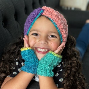 May include: A young person wearing a colorful, handmade crochet headband and fingerless gloves. The headband features sections of purple, teal, and pink with a sparkly thread. The fingerless gloves are teal and green with yellow trim, perfect for adding a touch of handmade charm.