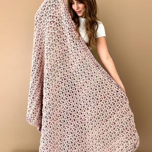 May include: A crocheted throw blanket in a pink and white color scheme with a delicate open stitch pattern.