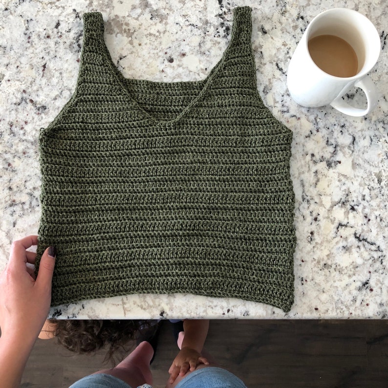May include: A green crochet tank top with a V-neck and thin straps.