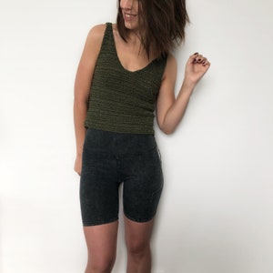 May include: A woman wearing a green crochet tank top and black biker shorts.