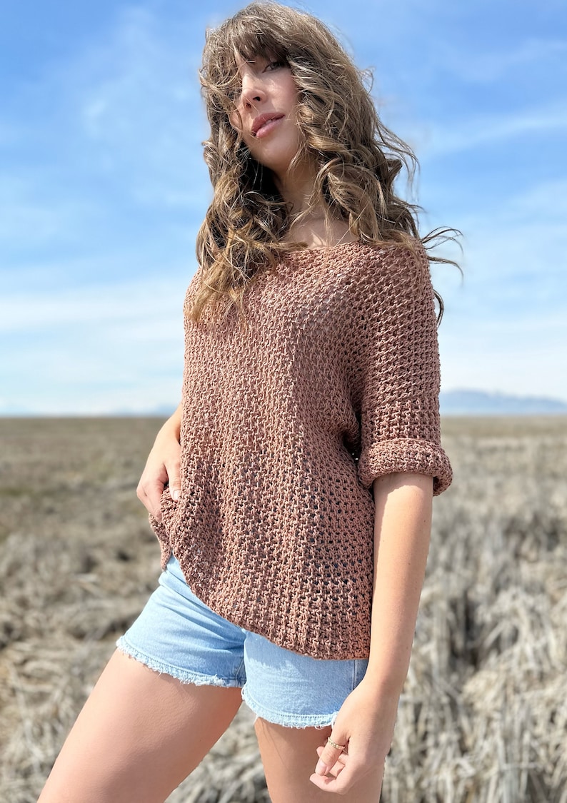 Puede incluir: Un su&eacute;ter de crochet marr&oacute;n de corte holgado y mangas cortas. El su&eacute;ter tiene un dise&ntilde;o texturizado de tejido abierto. La modelo lleva el su&eacute;ter con pantalones cortos de mezclilla.