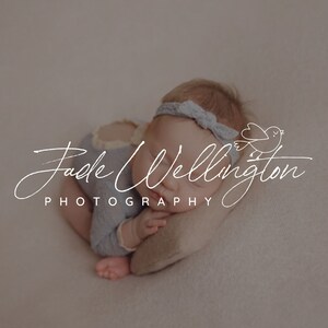 May include: A sleeping baby wearing a light blue onesie with a light blue headband. The baby is lying on a light brown blanket. The image includes the text "Jade Wellington Photography" with a small bird illustration.