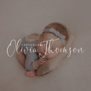 May include: A sleeping baby girl wearing a light blue onesie and a light blue headband with a bow. The text "Olivia Thompson CAPTURED BY" is written in cursive script.