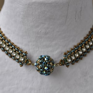 May include: A gold and blue beaded necklace with a large, round, blue and gold bead in the center.