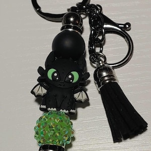 May include: Black and green beaded keychain with a black dragon charm and a black tassel.