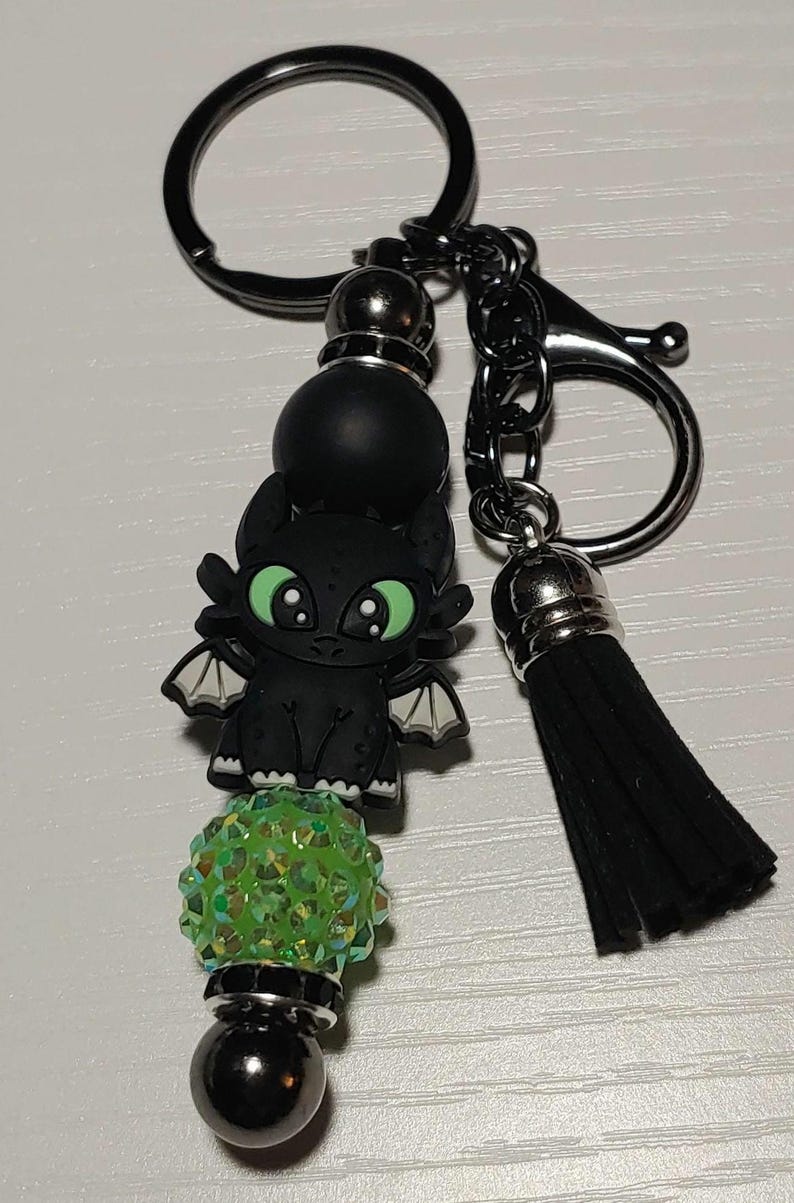 May include: Black and green beaded keychain with a black dragon charm and a black tassel.