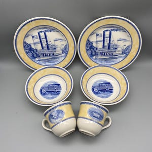 May include: A set of blue and white porcelain dinnerware with a steamboat design. The set includes two dinner plates, two bowls, and two cups.