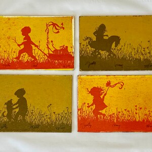 May include: Four rectangular art pieces with silhouettes of children at play. One shows a child pulling a cart, another a child riding a horse, a third a child with a dog, and the last a child with a ribbon. Each piece has a yellow and orange background.