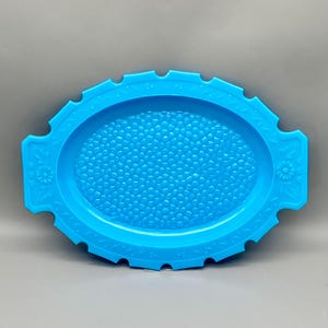 May include: A light blue oval serving tray with a textured surface and floral designs on the sides.