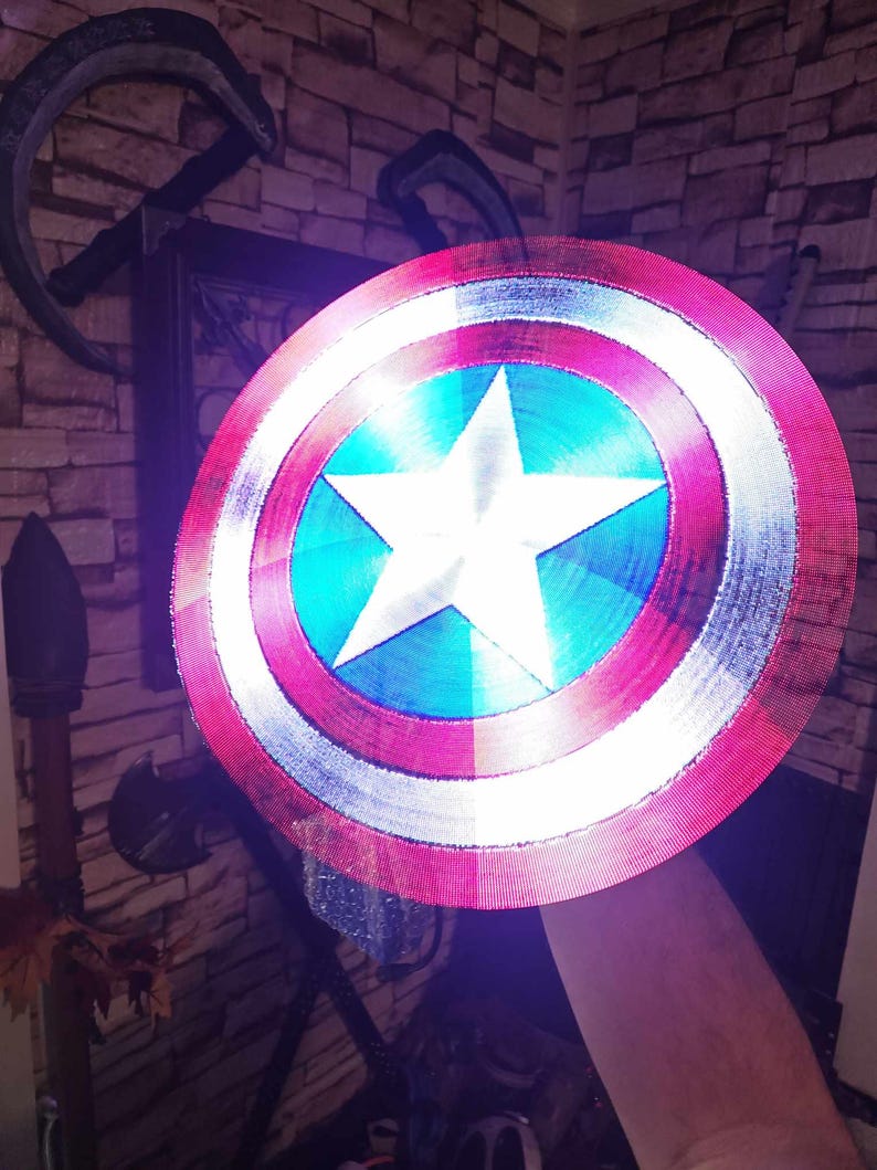 May include: A red, white, and blue Captain America shield with a white star in the center. The shield is made of plastic and has a 3D printed design.