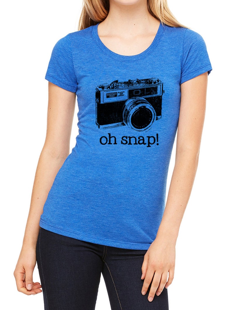 May include: A royal blue t-shirt with a black and white illustration of a vintage camera and the text "oh snap!"