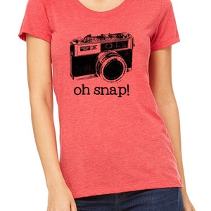May include: Red t-shirt with a black and white illustration of a vintage camera and the text "oh snap!"