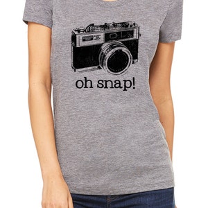 May include: A gray t-shirt with a black and white vintage camera graphic and the text "oh snap!" printed on the front.