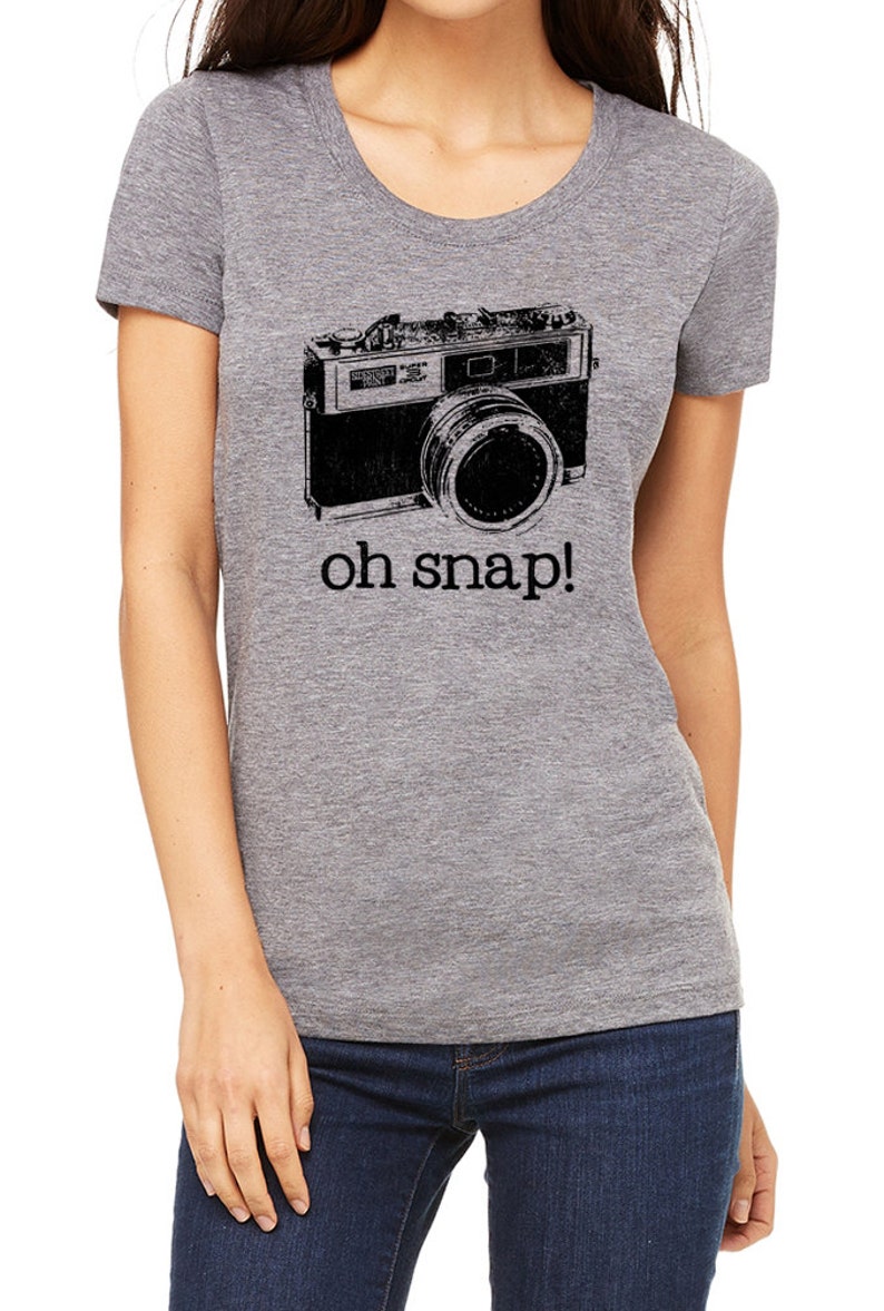 May include: A gray t-shirt with a black and white vintage camera graphic and the text "oh snap!" printed on the front.