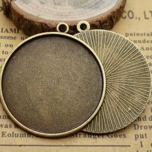 May include: A set of two antique bronze-coloured metal pendant trays. The tray on the left is smooth and the tray on the right has a sunburst design.