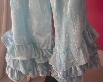 Op de afbeelding: Lichtblauwe fluwelen broek met een gefranjerde zoom. De broek heeft een brede, elastische tailleband en een zacht, getextureerd uiterlijk. De franjes voegen een decoratief element toe.