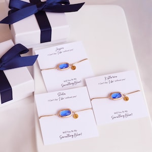 May include: Three white cards with blue and gold bracelets and personalized messages. The cards read "I Can't Say 'I do' without you!" and "Will You Be My Something Blue?"