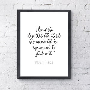May include: Black and white framed print with a white background and black text. The text reads "This is the day that the Lord has made, let us rejoice and be glad in it. Psalm 118:24".