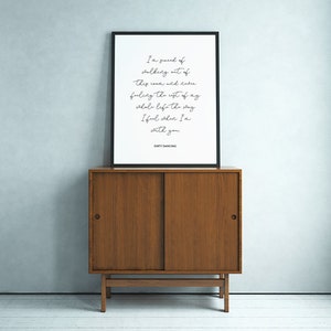May include: A black framed print with a white background and black text. The text reads "I'm scared of walking out of this room and never feeling the rest of my whole life the way I feel when I'm with you." The text is centered on the page and is in a cursive font. The bottom of the print reads "DIRTY DANCING".