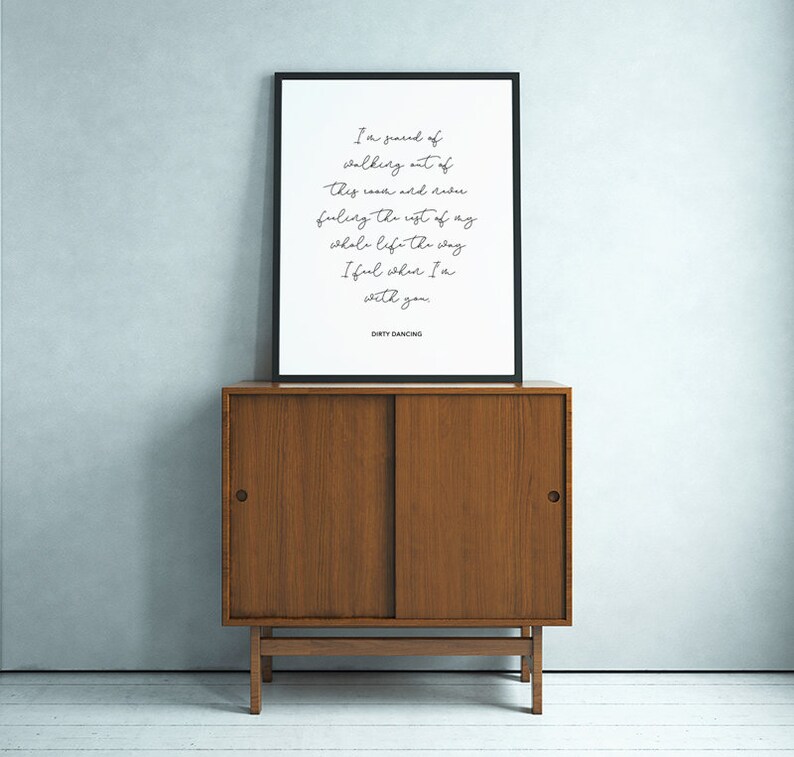 May include: A black framed print with a white background and black text. The text reads "I'm scared of walking out of this room and never feeling the rest of my whole life the way I feel when I'm with you." The text is centered on the page and is in a cursive font. The bottom of the print reads "DIRTY DANCING".