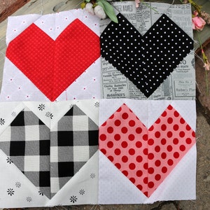 May include: Four fabric squares with heart-shaped designs. The top left square has a red heart on a white background with small white dots. The top right square has a black heart with white polka dots on a white background with small white dots. The bottom left square has a black and white checkered heart on a white background with small white flowers. The bottom right square has a pink heart with red polka dots on a white background with small white dots.