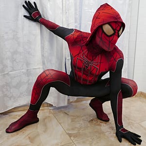 Puede incluir: Un traje de superh&eacute;roe de spandex rojo y negro con un dise&ntilde;o de telara&ntilde;a. El traje incluye una m&aacute;scara con capucha con un dise&ntilde;o de telara&ntilde;a y un logotipo de ara&ntilde;a rojo y negro en el pecho.