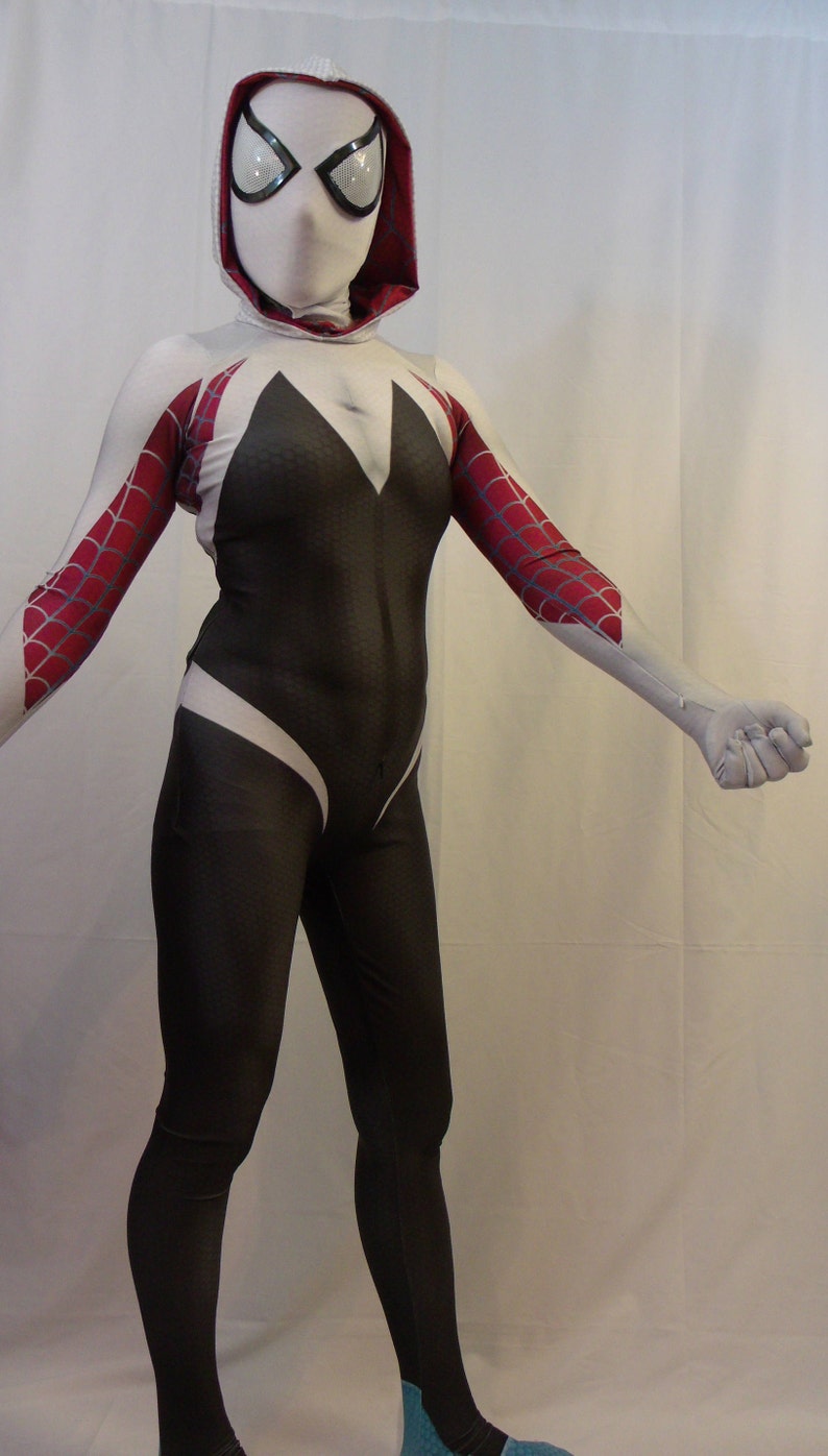 Puede incluir: Un traje de spandex blanco y negro con un dise&ntilde;o de telara&ntilde;a roja y blanca en los brazos. El traje tiene una m&aacute;scara blanca con capucha y un dise&ntilde;o de telara&ntilde;a negra.