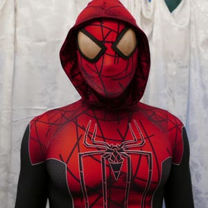 Puede incluir: Un traje de Spiderman rojo y negro con un logotipo de ara&ntilde;a negro en el pecho. El traje tiene una m&aacute;scara roja con capucha y ojos de malla negra.