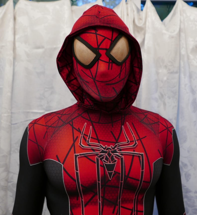Puede incluir: Un traje de Spiderman rojo y negro con un logotipo de ara&ntilde;a negro en el pecho. El traje tiene una m&aacute;scara roja con capucha y ojos de malla negra.