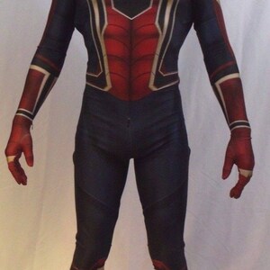 May include: A red and blue spandex costume with a spider web design. The costume has a black mask with a white spider logo. The costume is worn by a person standing on a white background.